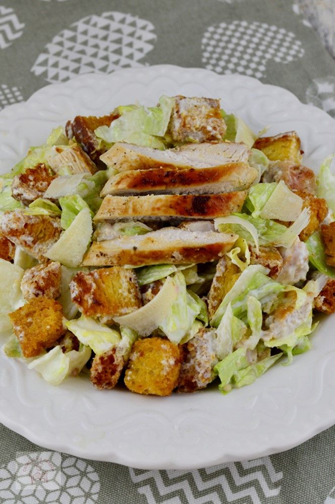 a white plate topped with a salad covered in lettuce and chicken meats