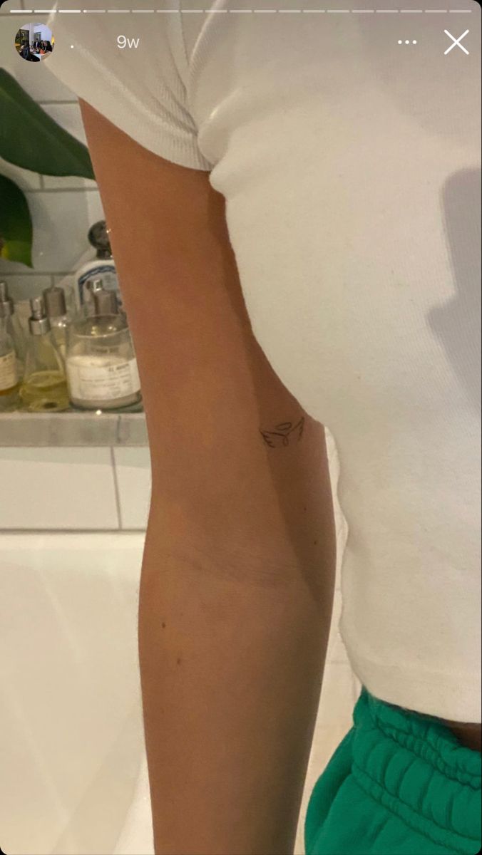 a woman's arm with a tattoo on it in front of a bathroom mirror