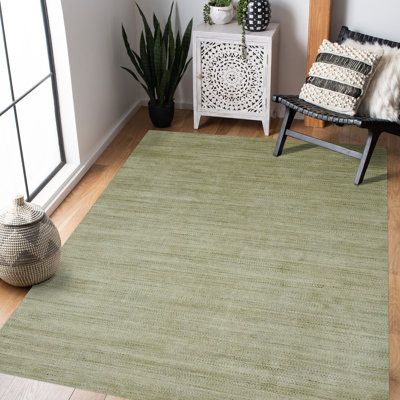 a green rug in the corner of a room next to a chair and potted plant