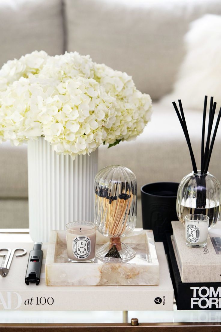 a white vase filled with flowers on top of a table next to candles and other items