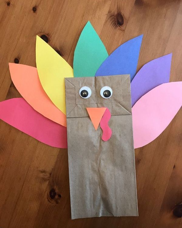 a paper bag shaped like a turkey with eyes on it's head and leaves around its neck