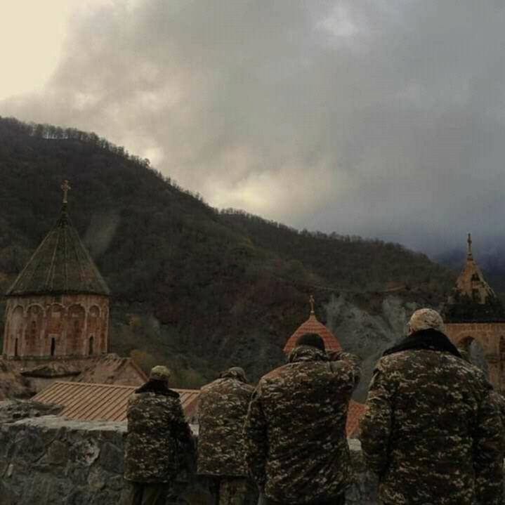 three soldiers are standing in front of a mountain with a church on it's side