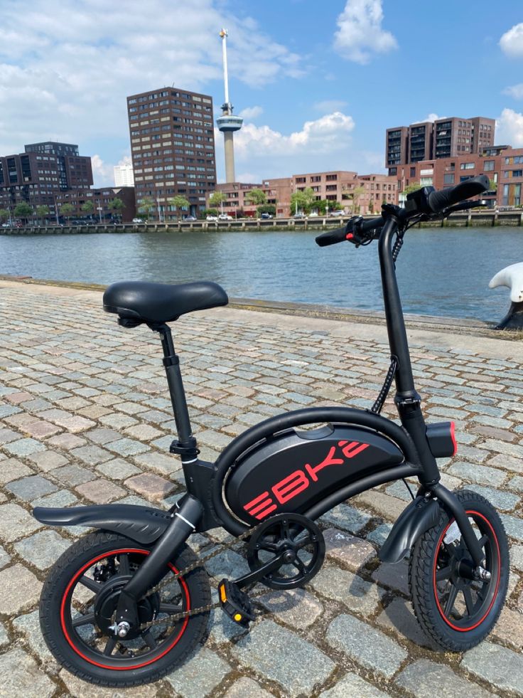 an electric scooter is parked on the sidewalk by the water in front of some buildings