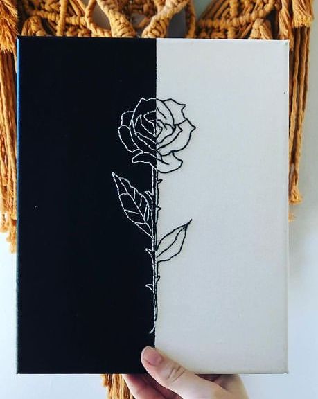 a hand holding a black and white book with a rose on it