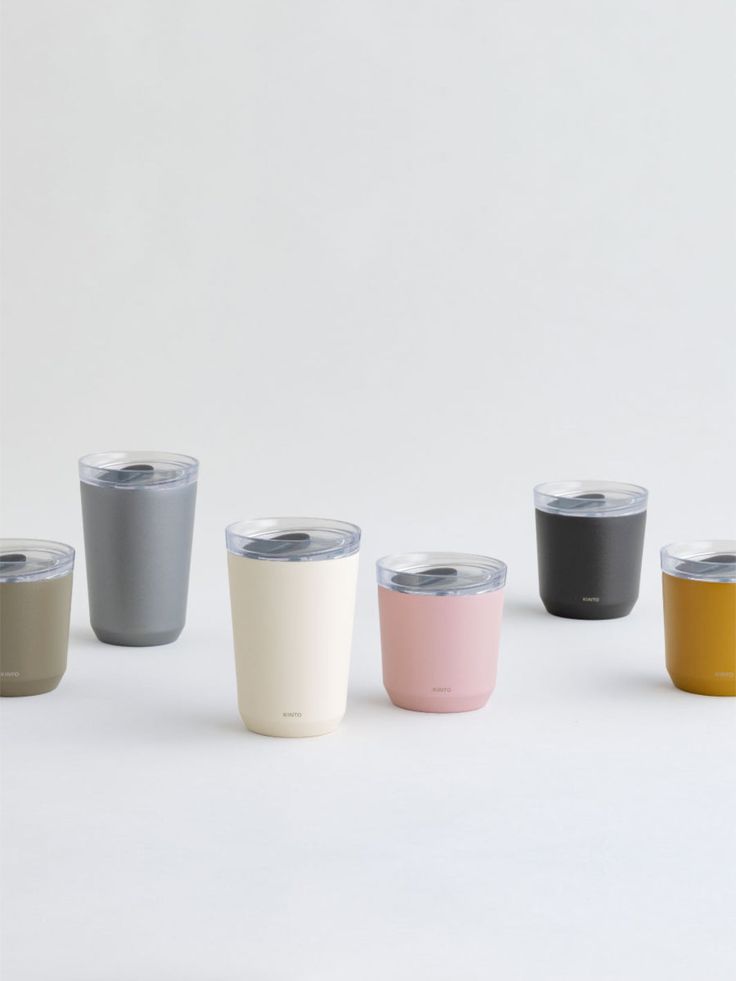 six different colored tumblers sitting next to each other on a white surface with one cup in the middle