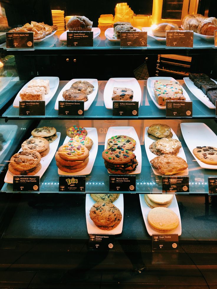 a display case filled with lots of different types of cakes and pies on plates