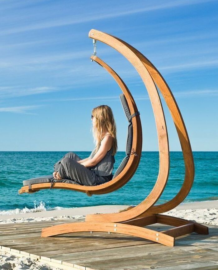 a woman sitting on a wooden bench near the ocean