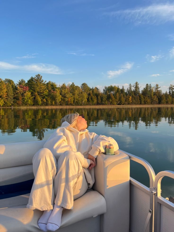 a woman sitting on the back of a boat in front of a body of water