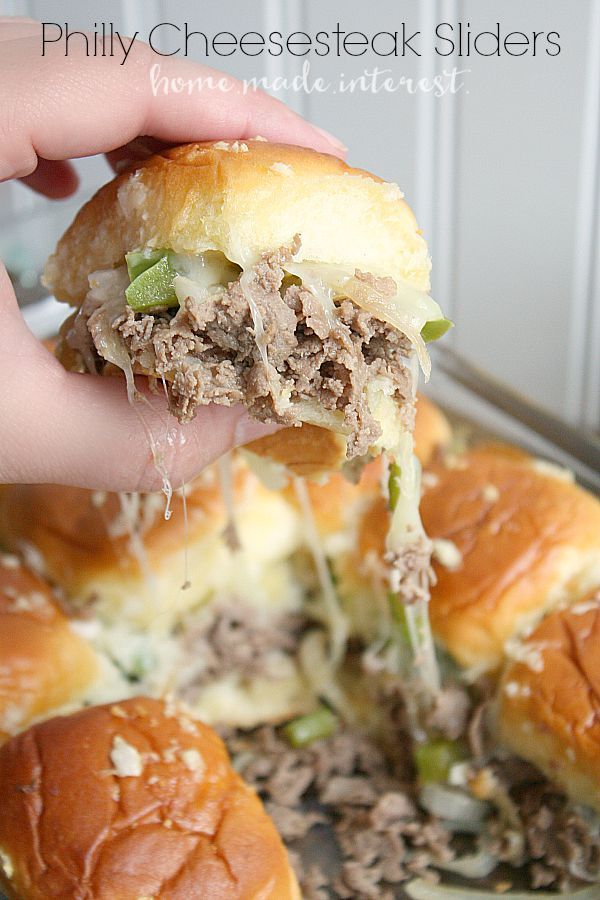 someone is taking a bite out of a pulled pork slider with melted cheese and green onions