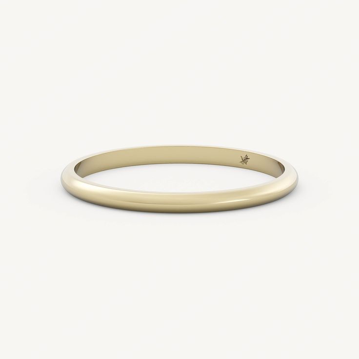 a thin yellow gold wedding band with a small diamond in the center, on a white background