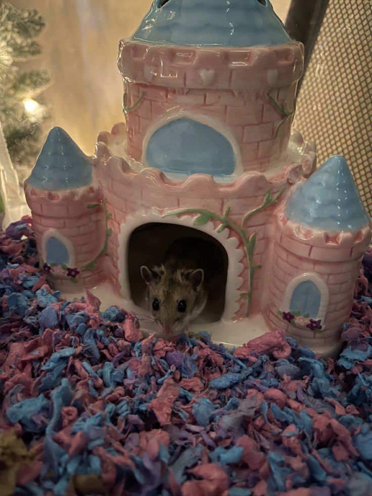 a toy mouse peeking out of a pink and blue castle