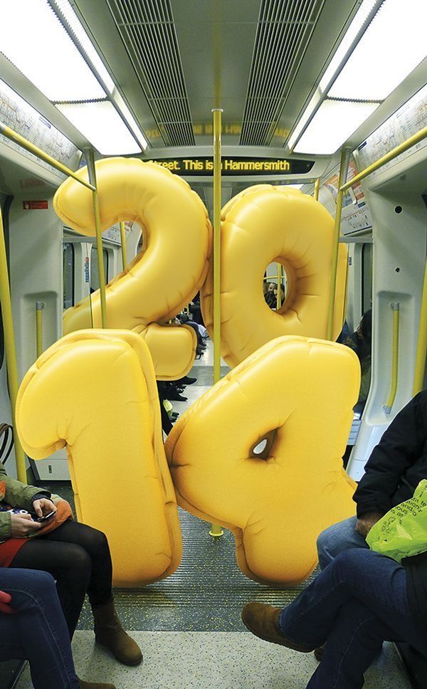 two people sitting on a subway train with giant letters in the shape of 2 and 3