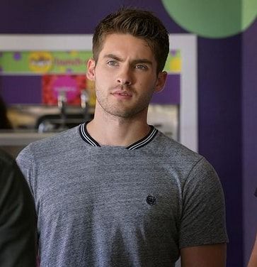 a young man standing in front of a purple wall