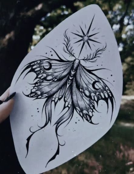 a drawing of a butterfly on a white piece of paper with trees in the background