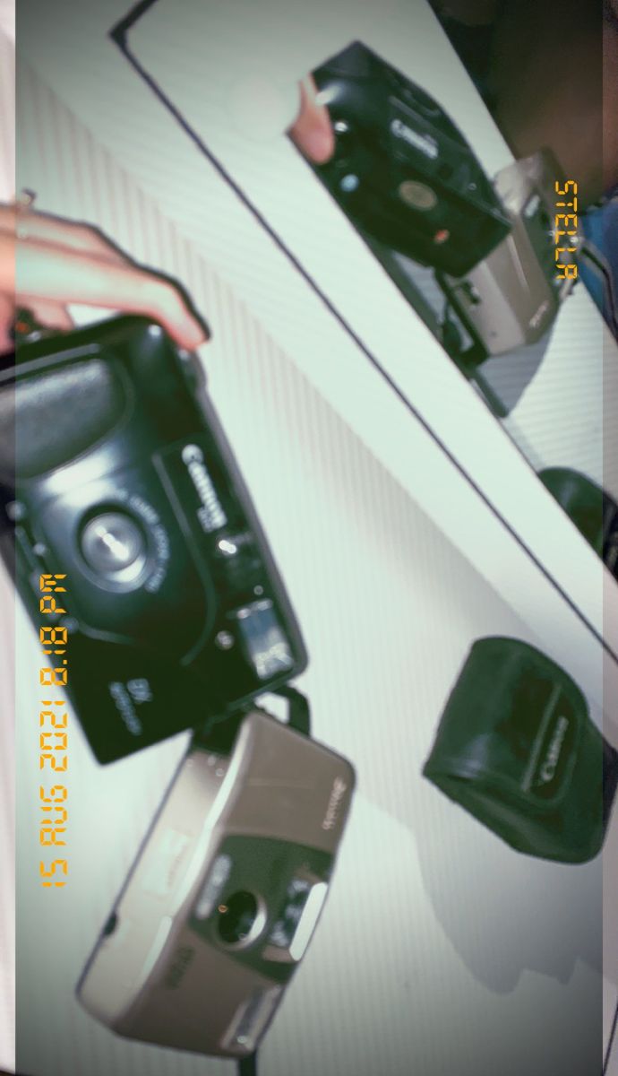 a person holding an old camera in their left hand and another one on the other