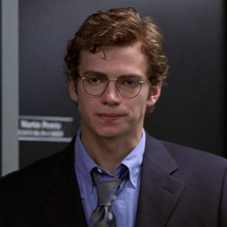 a young man wearing glasses and a suit