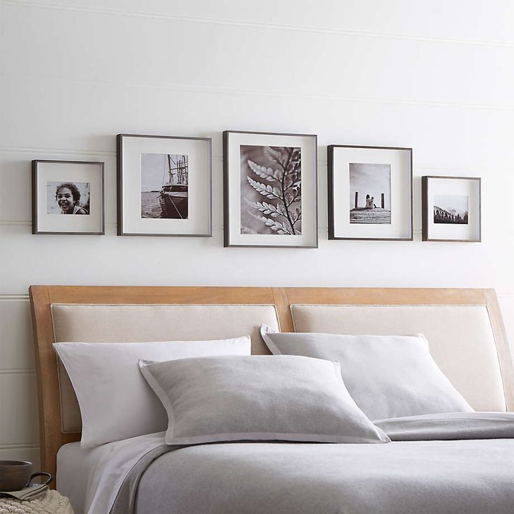 a bed with white linens and pictures on the wall above it in a bedroom