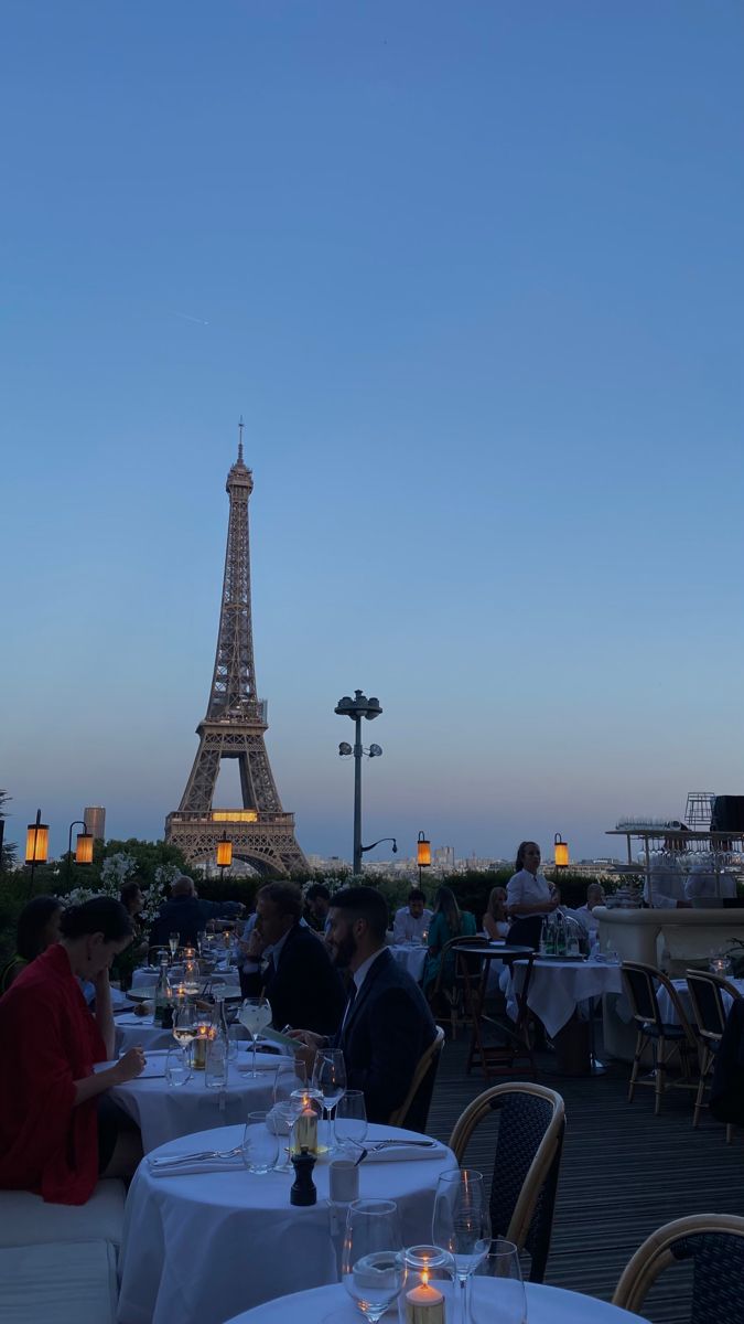 people sitting at tables in front of the eiffel tower