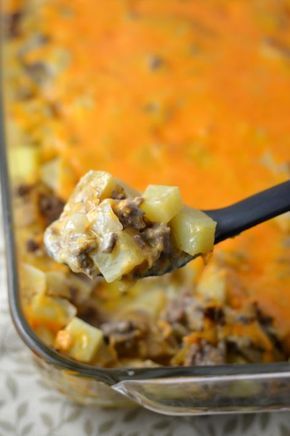 a spoon full of food in a casserole dish with cheese and other toppings