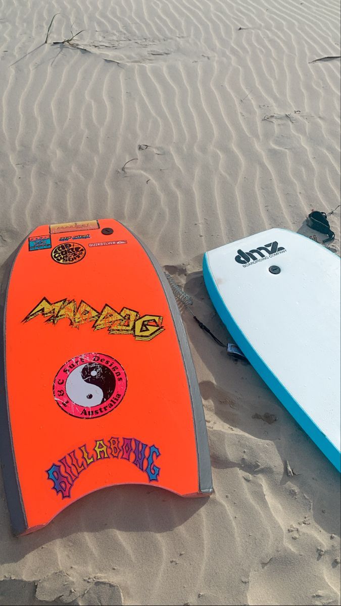 two surfboards laying on the sand at the beach