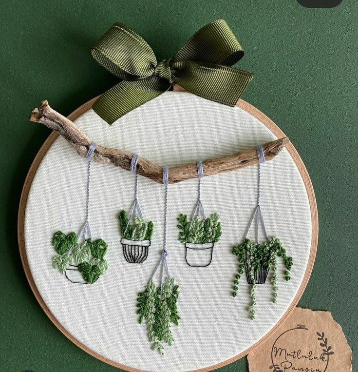 a cross stitch pattern with potted plants hanging on a branch and tied in twine