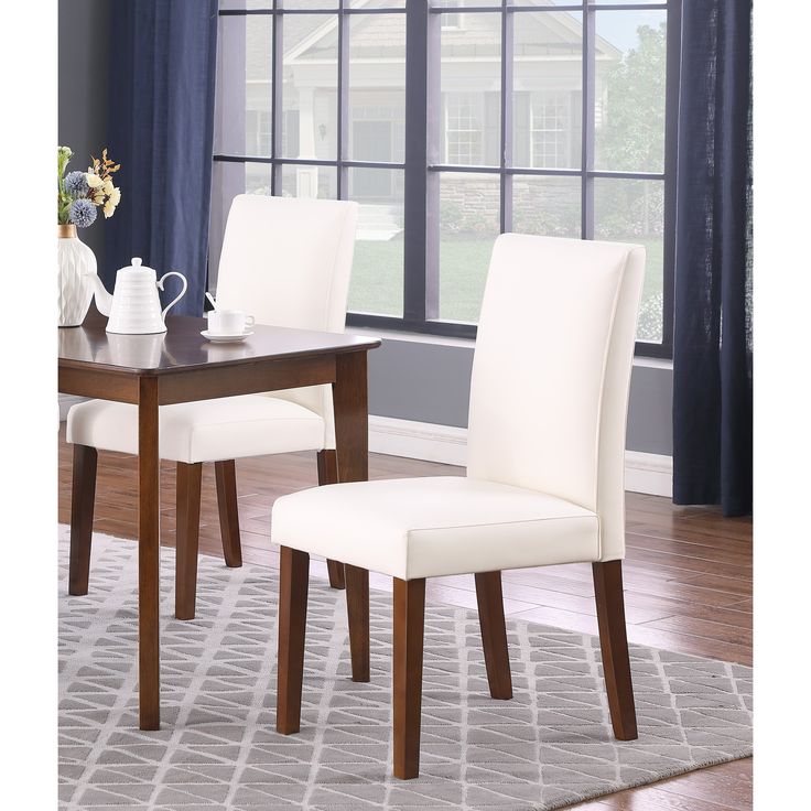 a dining room table with two chairs and a rug on the floor in front of it