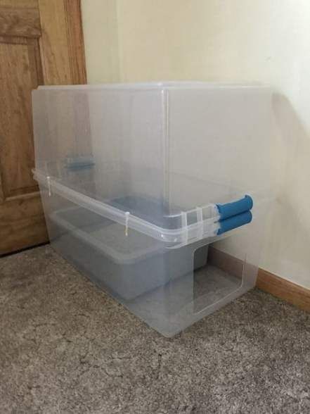 two plastic storage containers sitting on the floor in front of a door with blue handles