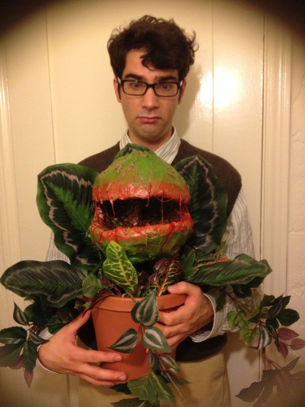 a man holding a potted plant with a monster's mouth painted on it