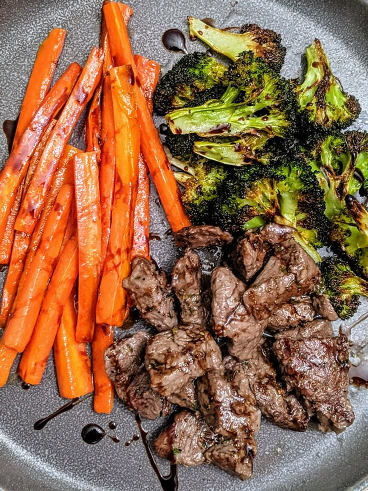 some meat and carrots on a plate with broccoli