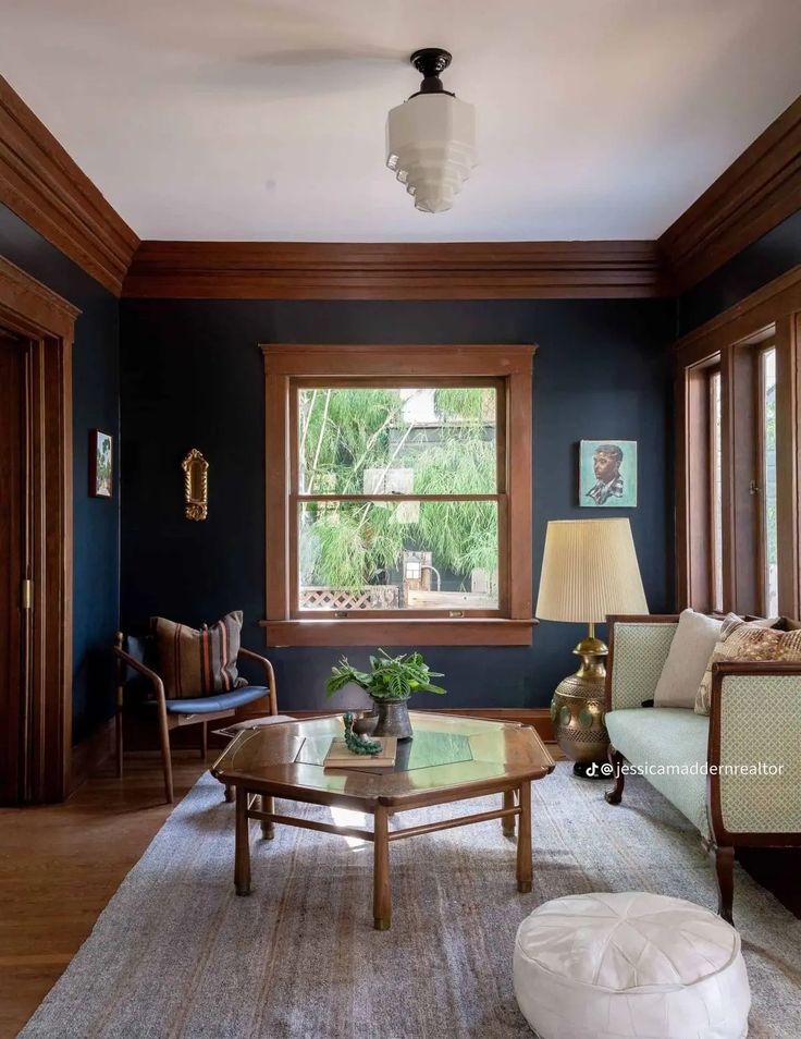 a living room with blue walls and wood trimming on the ceiling, two couches in front of a coffee table