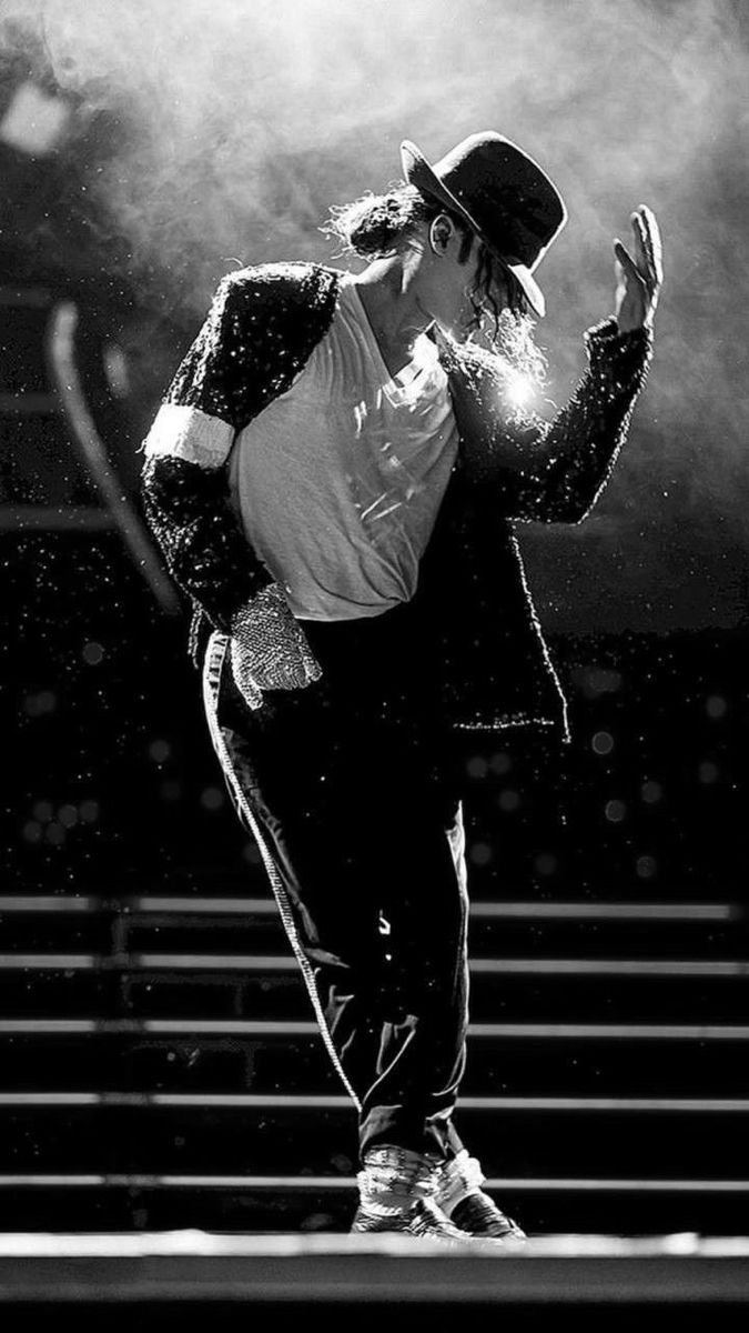 a male in a white shirt and black pants is dancing with his hands up to his face