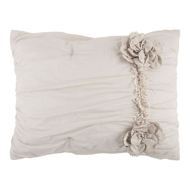 a white pillow with ruffled edges and flowers on the front, sitting against a white background