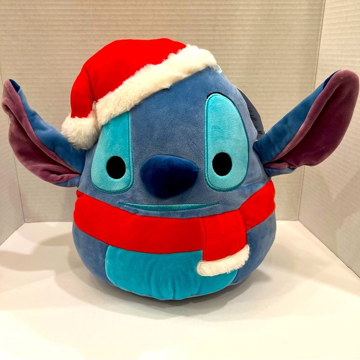 a stuffed animal with a santa hat and scarf on it's head sitting on a table