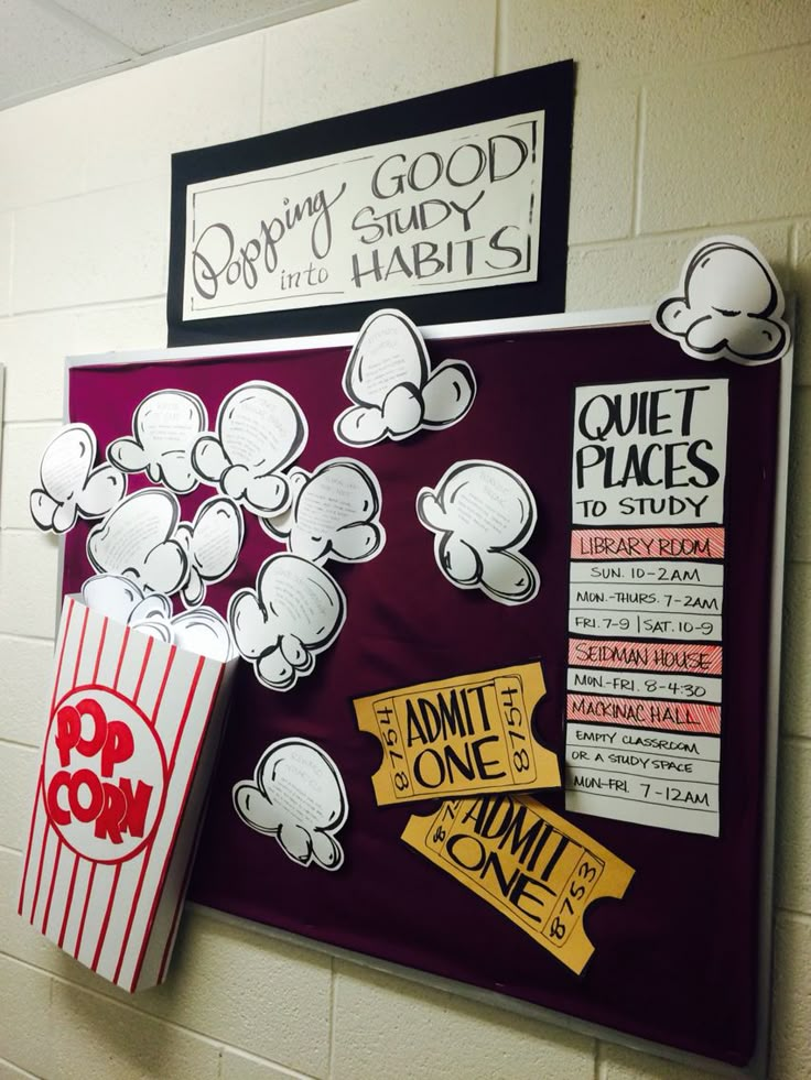 a bulletin board with popcorn, movie tickets and other signs on it in a school hallway