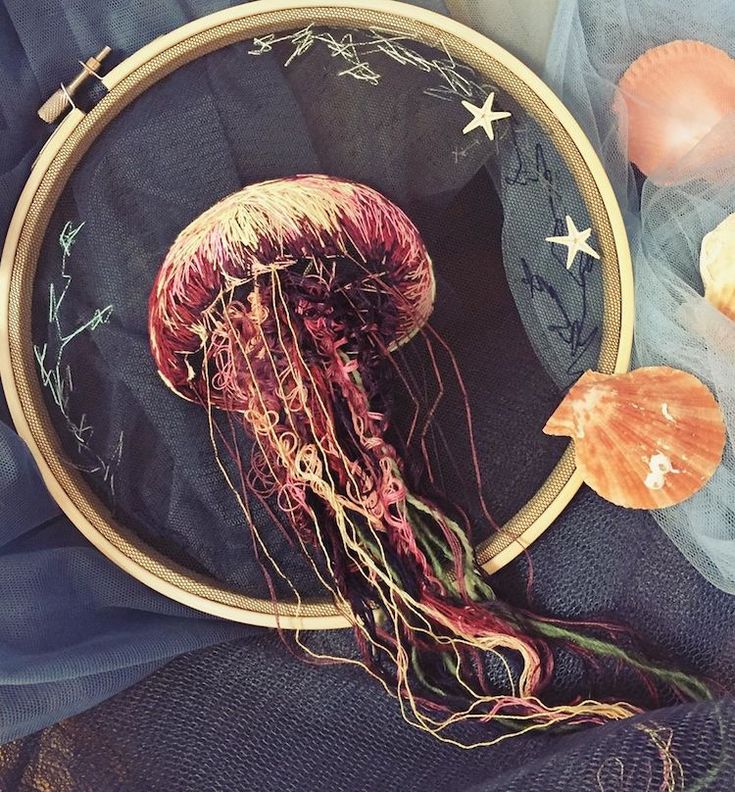 a close up of a jellyfish in a hoop with sea shells on the ground