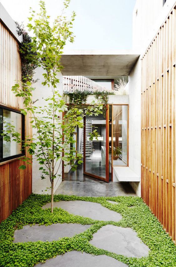 the walkway is lined with green grass and stone stepping stones that lead to an entrance