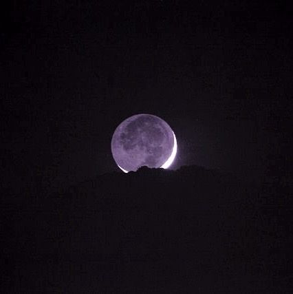 the full moon is seen in the dark sky above a mountain range at night time