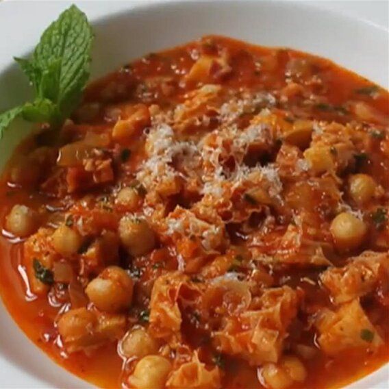 a white bowl filled with stew and garnished with parmesan cheese on top