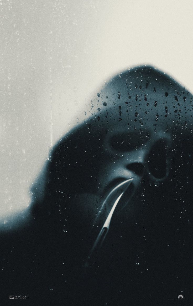 a black and white photo of a person's face through a rain covered window