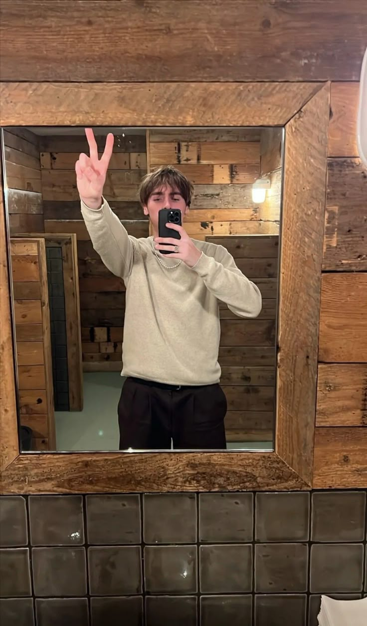 a man taking a selfie in front of a mirror with his hand up to the camera