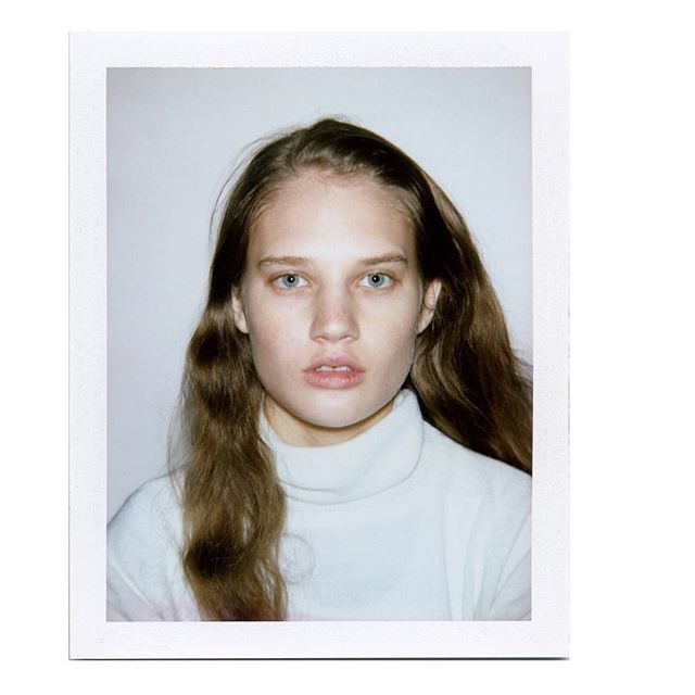 a young woman with long hair wearing a white turtle neck sweater and looking at the camera