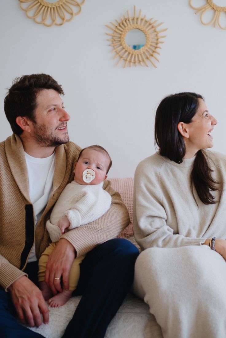 a man and woman sitting on a couch holding a baby