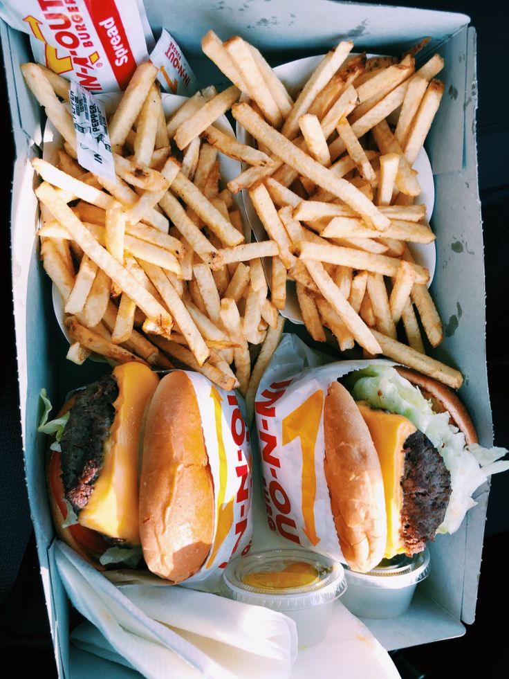 two cheeseburgers and fries in a box with french fries on the table next to them