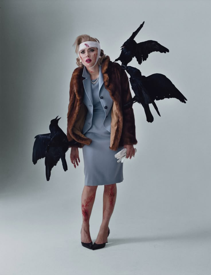 a woman in a dress and coat with birds on her head, posing for a photo