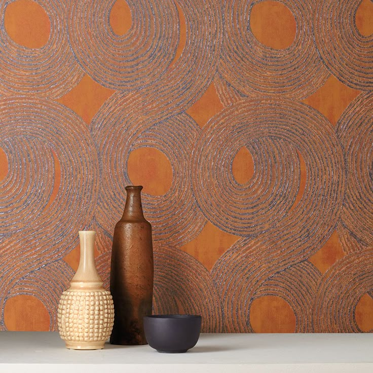 two vases are sitting on a shelf in front of an orange wallpaper