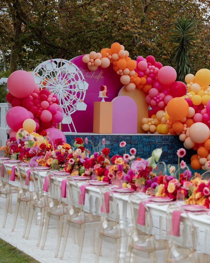 a long table with many balloons and flowers on it