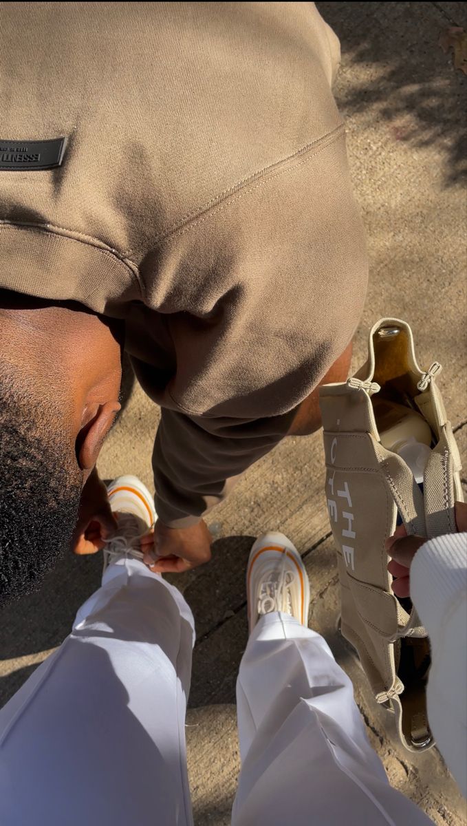 a man with his foot on the ground next to someone's feet wearing white shoes