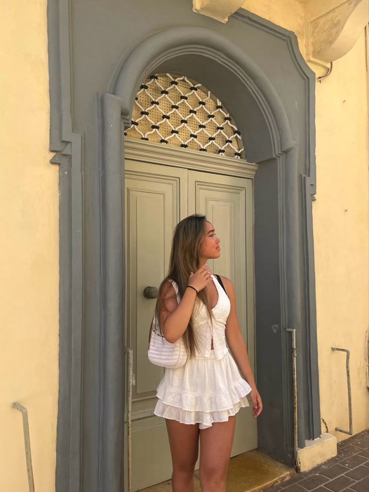 a beautiful young woman standing in front of a door