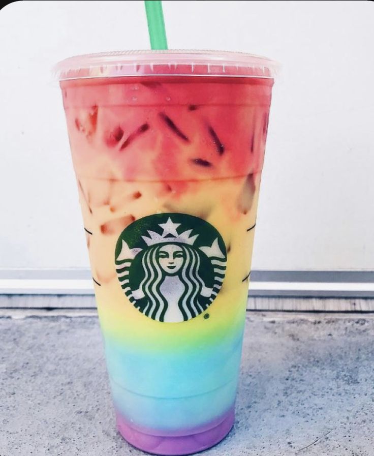 a starbucks drink with a straw in it sitting on the ground next to a wall