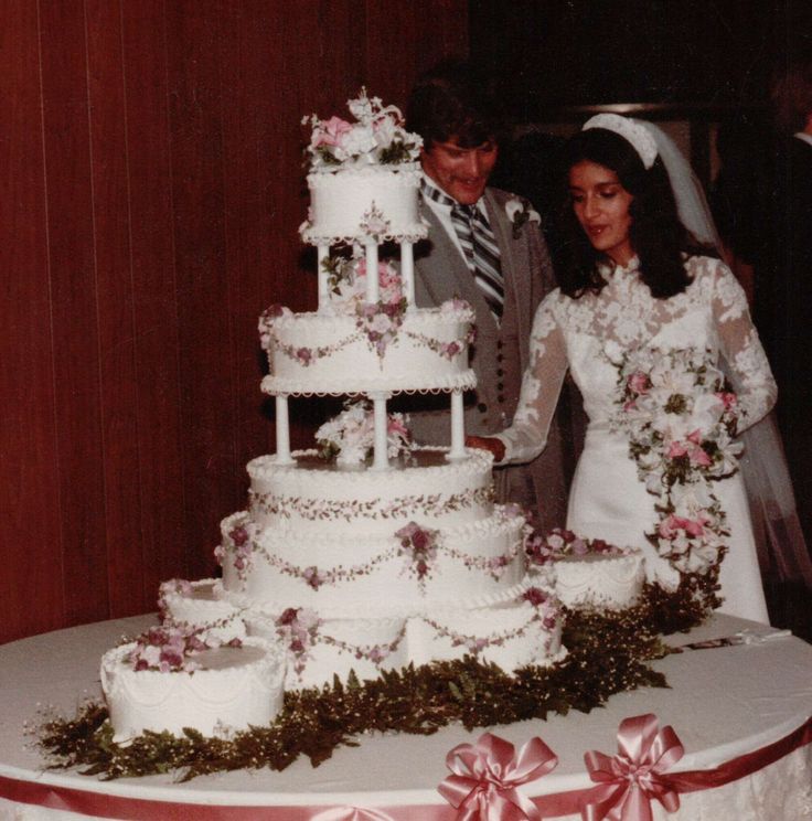 a man and woman standing next to a wedding cake